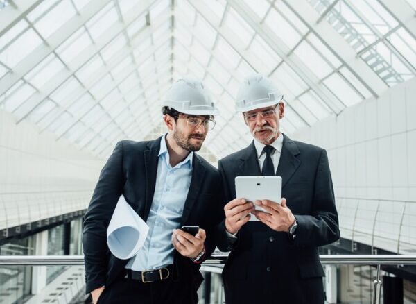 two-successful-entrepreneur-helmet-with-project-laptop-new-buildings-stay-near-glass-roof_496169-971